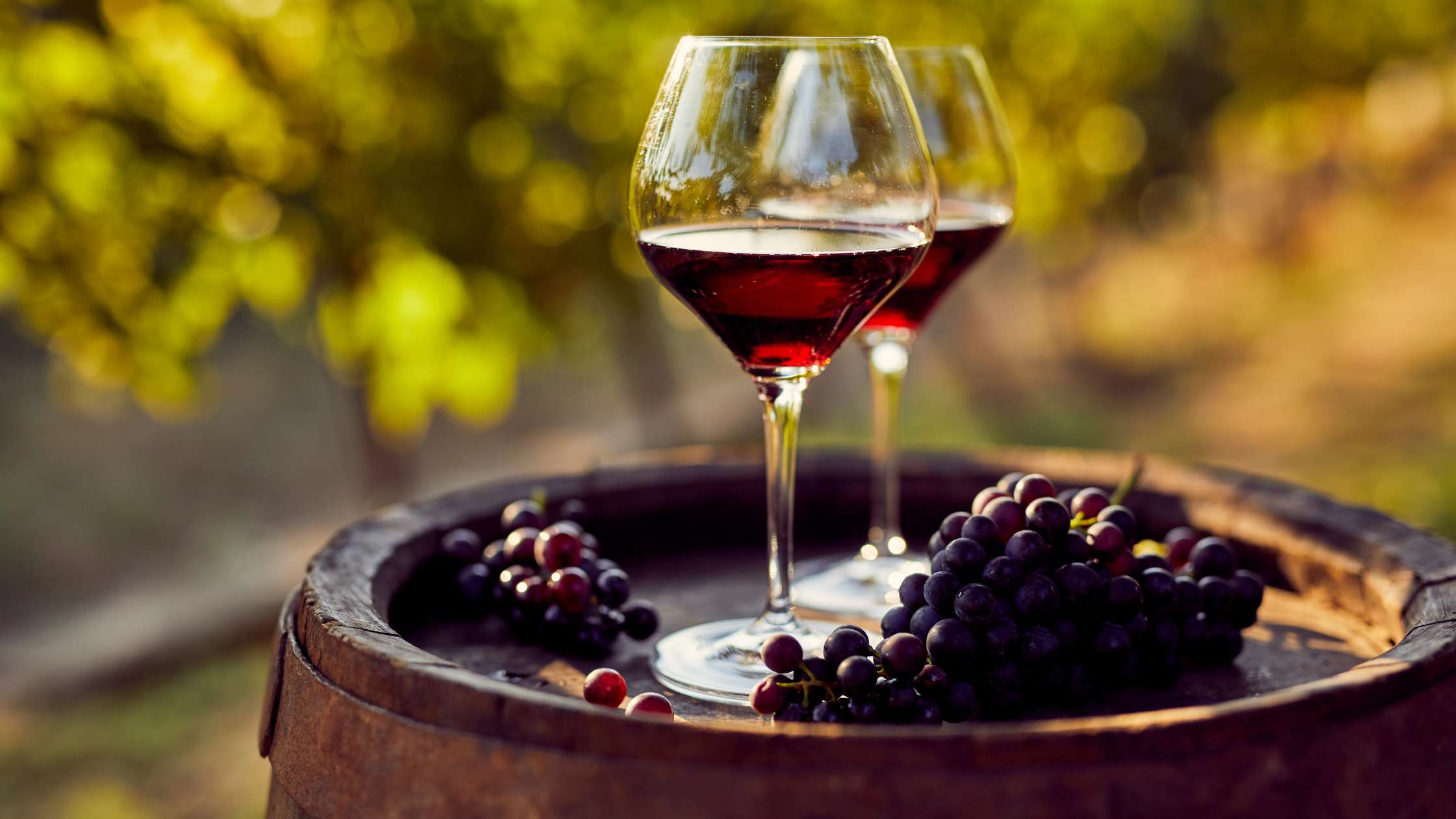 Wine glasses and grapes on a barrel